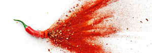 A cayenne pepper displayed from the whole top to slices and powder against a white background