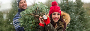 man and woman carrying freshly cut christmas tree